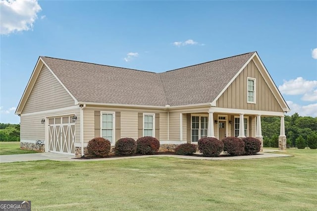 view of front of home featuring a garage, covered porch, and a front lawn