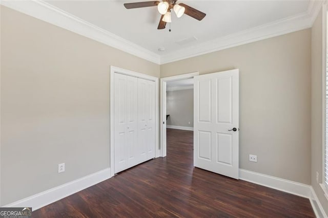 unfurnished bedroom with ornamental molding, dark wood-type flooring, ceiling fan, and a closet