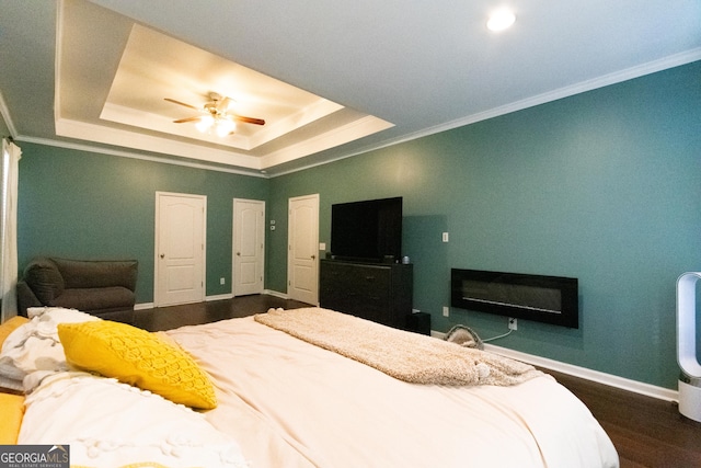 bedroom with ceiling fan, hardwood / wood-style floors, crown molding, and a raised ceiling