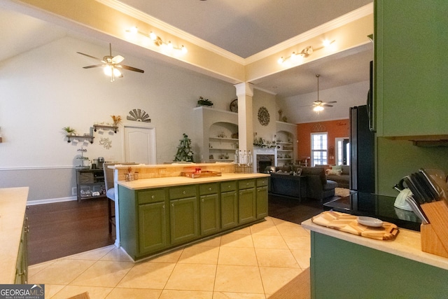 kitchen featuring light tile patterned flooring, vaulted ceiling, ornamental molding, green cabinetry, and stainless steel refrigerator