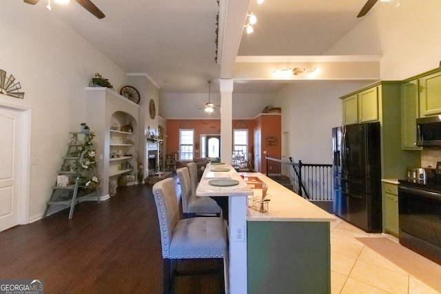 kitchen with range, lofted ceiling, black fridge, ceiling fan, and green cabinets