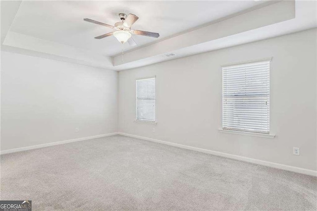 unfurnished room with carpet floors, ceiling fan, and a raised ceiling