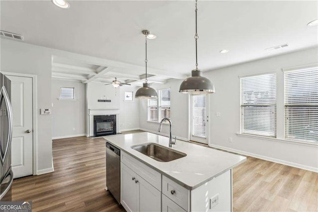 kitchen with beamed ceiling, coffered ceiling, white cabinetry, sink, and stainless steel appliances