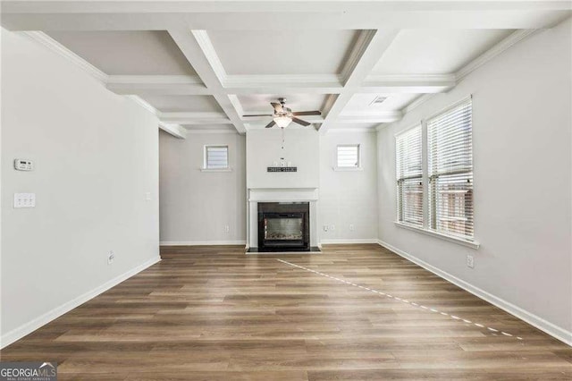 unfurnished living room featuring ceiling fan, ornamental molding, hardwood / wood-style flooring, beam ceiling, and coffered ceiling