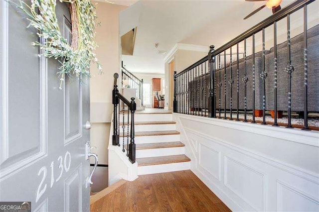 stairs with hardwood / wood-style flooring and crown molding