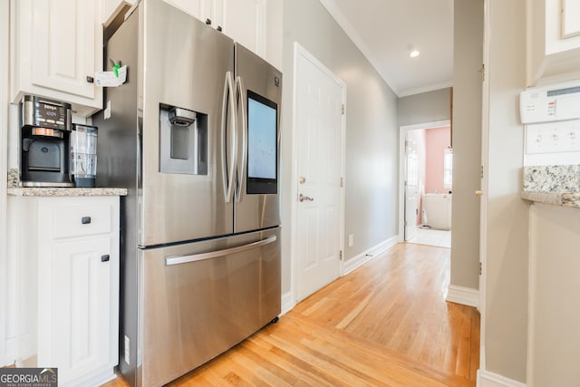 kitchen featuring stainless steel refrigerator with ice dispenser, white cabinetry, light wood-type flooring, and ornamental molding