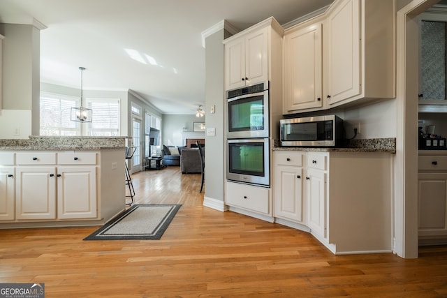 kitchen featuring crown molding, appliances with stainless steel finishes, white cabinets, light hardwood / wood-style flooring, and pendant lighting