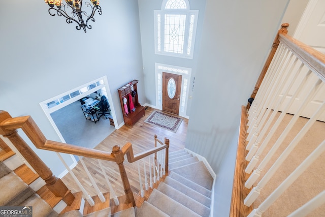 foyer entrance featuring hardwood / wood-style flooring, a high ceiling, and a notable chandelier