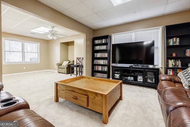 living room featuring a paneled ceiling, light colored carpet, and ceiling fan