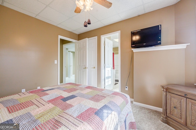 carpeted bedroom with ceiling fan, connected bathroom, and a drop ceiling