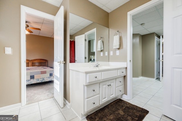 bathroom with a drop ceiling, tile patterned flooring, ceiling fan, and vanity