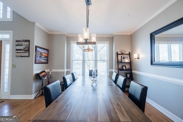 dining area with crown molding, wood-type flooring, and an inviting chandelier