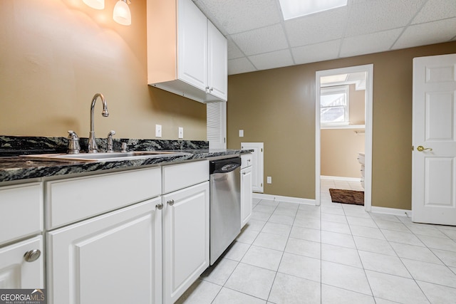 kitchen with dishwasher, white cabinets, sink, dark stone counters, and light tile patterned flooring