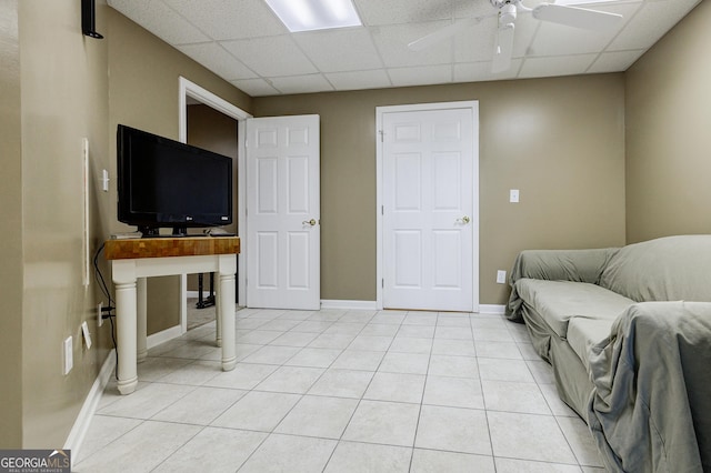 living room featuring a paneled ceiling, light tile patterned floors, and ceiling fan