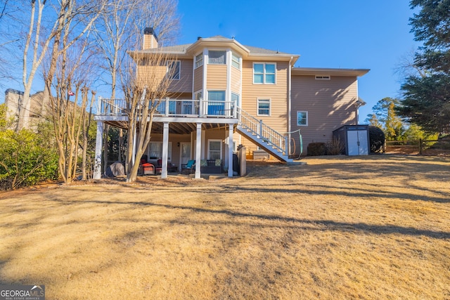 back of property with a shed, a lawn, and a wooden deck