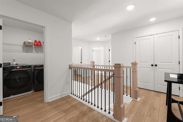 corridor featuring light wood-type flooring and separate washer and dryer