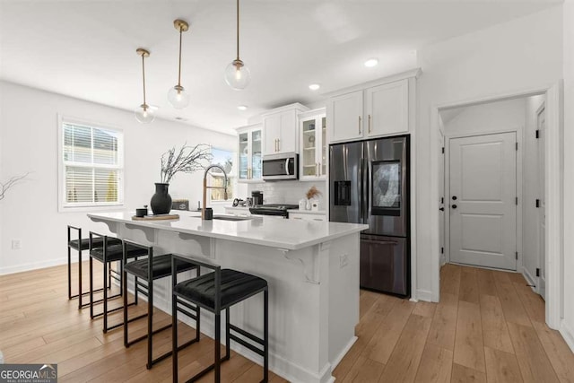 kitchen featuring tasteful backsplash, white cabinetry, hanging light fixtures, a breakfast bar, and stainless steel appliances