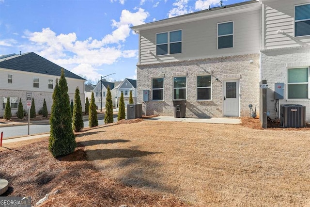 back of house with central AC unit and a lawn