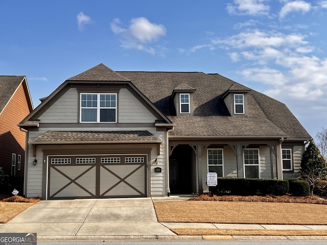 view of front of house featuring a shingled roof, concrete driveway, and a garage