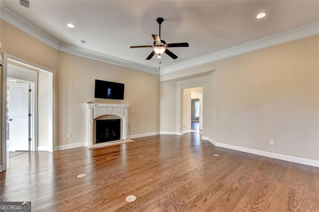 unfurnished living room featuring baseboards, ceiling fan, ornamental molding, wood finished floors, and a fireplace