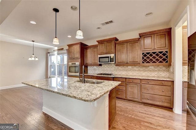 kitchen featuring stainless steel appliances, light wood finished floors, a sink, and visible vents