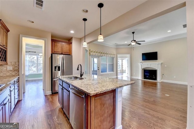 kitchen featuring visible vents, appliances with stainless steel finishes, a sink, a fireplace, and backsplash