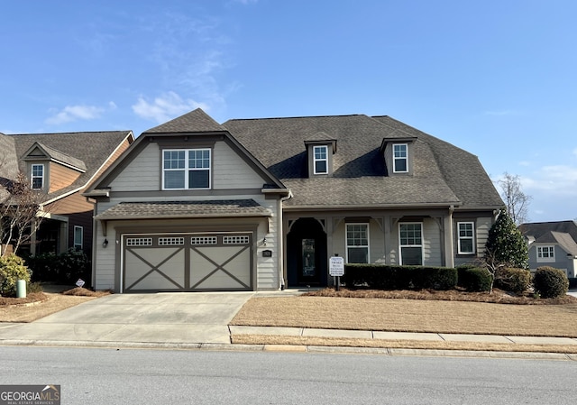 craftsman-style house with an attached garage, a shingled roof, and concrete driveway