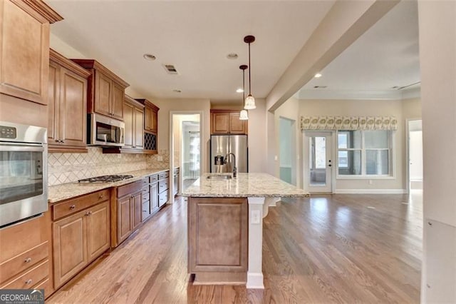 kitchen with light stone counters, stainless steel appliances, tasteful backsplash, visible vents, and light wood-type flooring