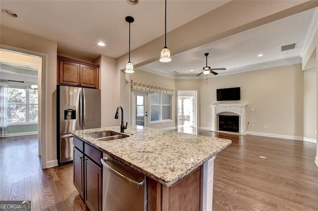 kitchen featuring visible vents, wood finished floors, stainless steel appliances, a fireplace, and a sink