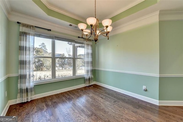 unfurnished dining area with baseboards, wood finished floors, an inviting chandelier, a tray ceiling, and crown molding