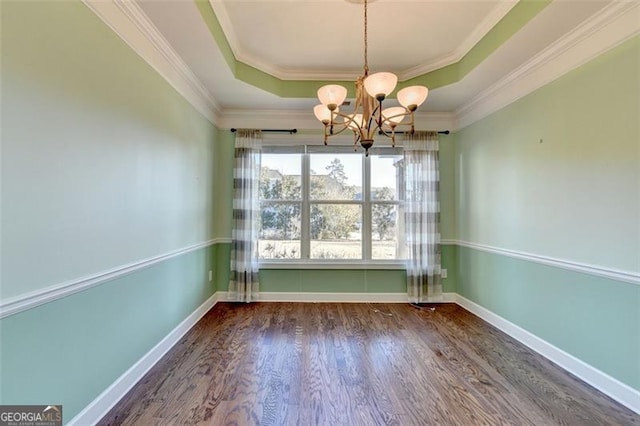 unfurnished dining area with a notable chandelier, wood finished floors, baseboards, a tray ceiling, and crown molding