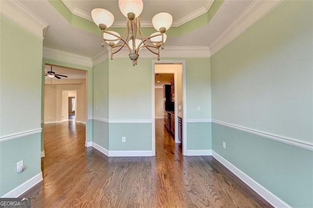 unfurnished dining area featuring baseboards, a raised ceiling, wood finished floors, crown molding, and ceiling fan with notable chandelier