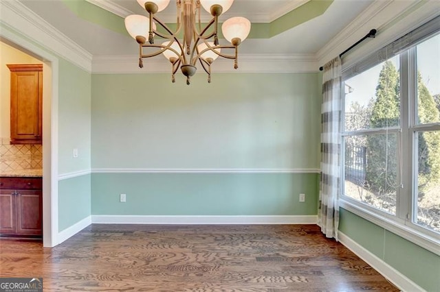 unfurnished dining area featuring baseboards, a raised ceiling, dark wood-style floors, ornamental molding, and a notable chandelier