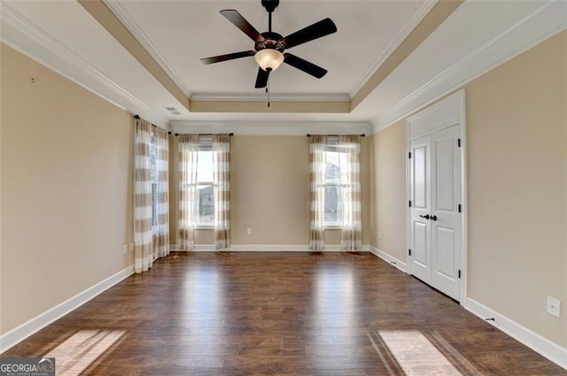 unfurnished room with dark wood-style floors, crown molding, a raised ceiling, and baseboards