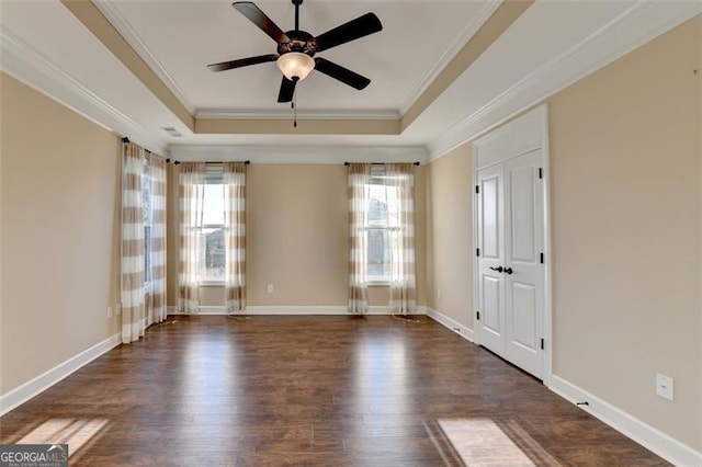 unfurnished room with crown molding, a tray ceiling, and dark wood-style flooring