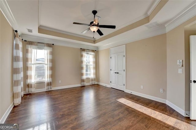 spare room featuring a raised ceiling, crown molding, baseboards, and wood finished floors