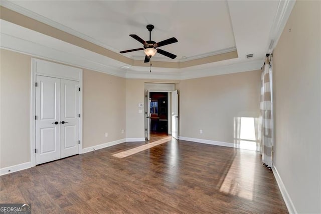 unfurnished room with baseboards, a raised ceiling, ceiling fan, wood finished floors, and crown molding