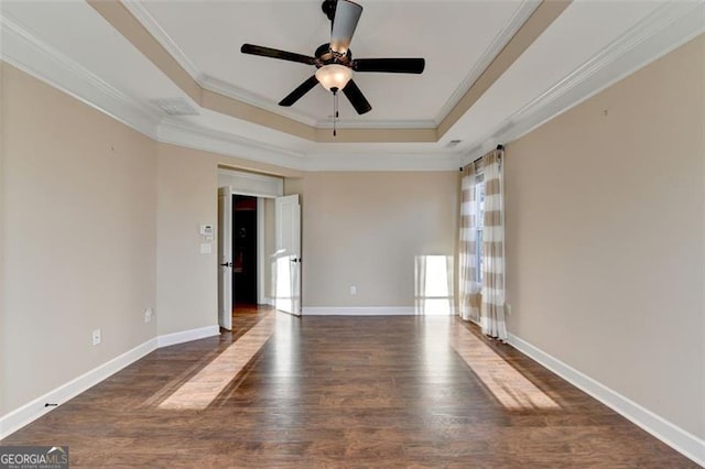 spare room featuring wood finished floors, ornamental molding, a raised ceiling, and baseboards