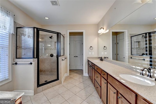 bathroom with double vanity, a stall shower, visible vents, and a sink