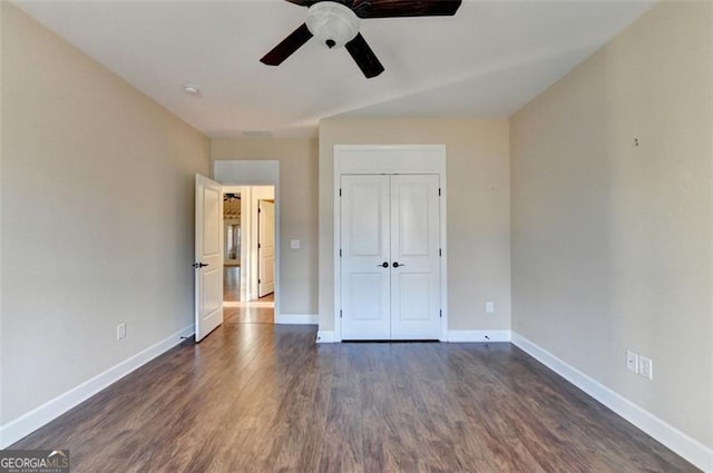 unfurnished bedroom with ceiling fan, a closet, baseboards, and dark wood-type flooring