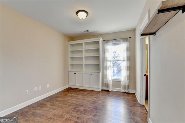 unfurnished bedroom featuring dark wood finished floors, visible vents, and baseboards