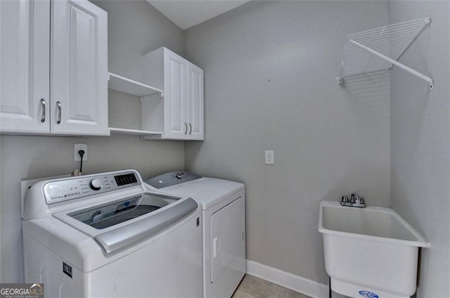 laundry area with light tile patterned flooring, separate washer and dryer, a sink, baseboards, and cabinet space