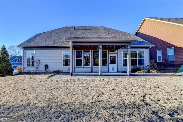 rear view of house featuring roof with shingles, a lawn, and a patio