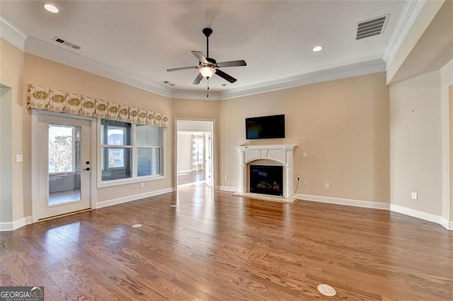 unfurnished living room featuring crown molding, visible vents, wood finished floors, and a glass covered fireplace