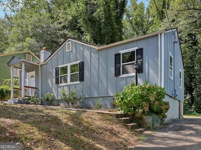 bungalow featuring a chimney and board and batten siding