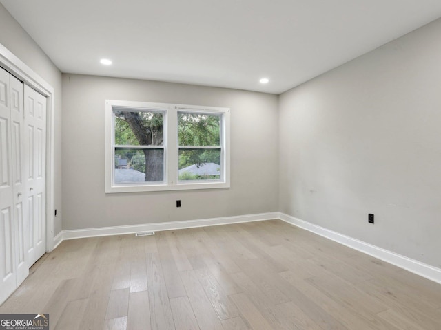 unfurnished bedroom with visible vents, a closet, light wood finished floors, and baseboards