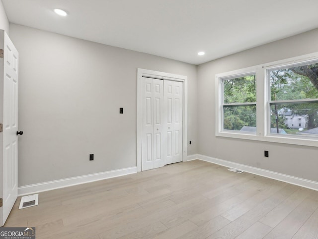 unfurnished bedroom featuring recessed lighting, a closet, light wood-type flooring, visible vents, and baseboards
