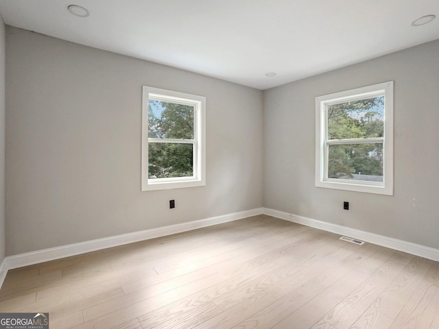 spare room with a wealth of natural light, visible vents, light wood-style flooring, and baseboards