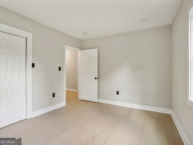 unfurnished bedroom featuring a closet, light wood-style flooring, and baseboards