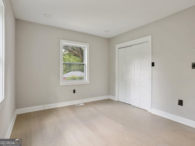 unfurnished bedroom with baseboards, visible vents, a closet, and light wood finished floors